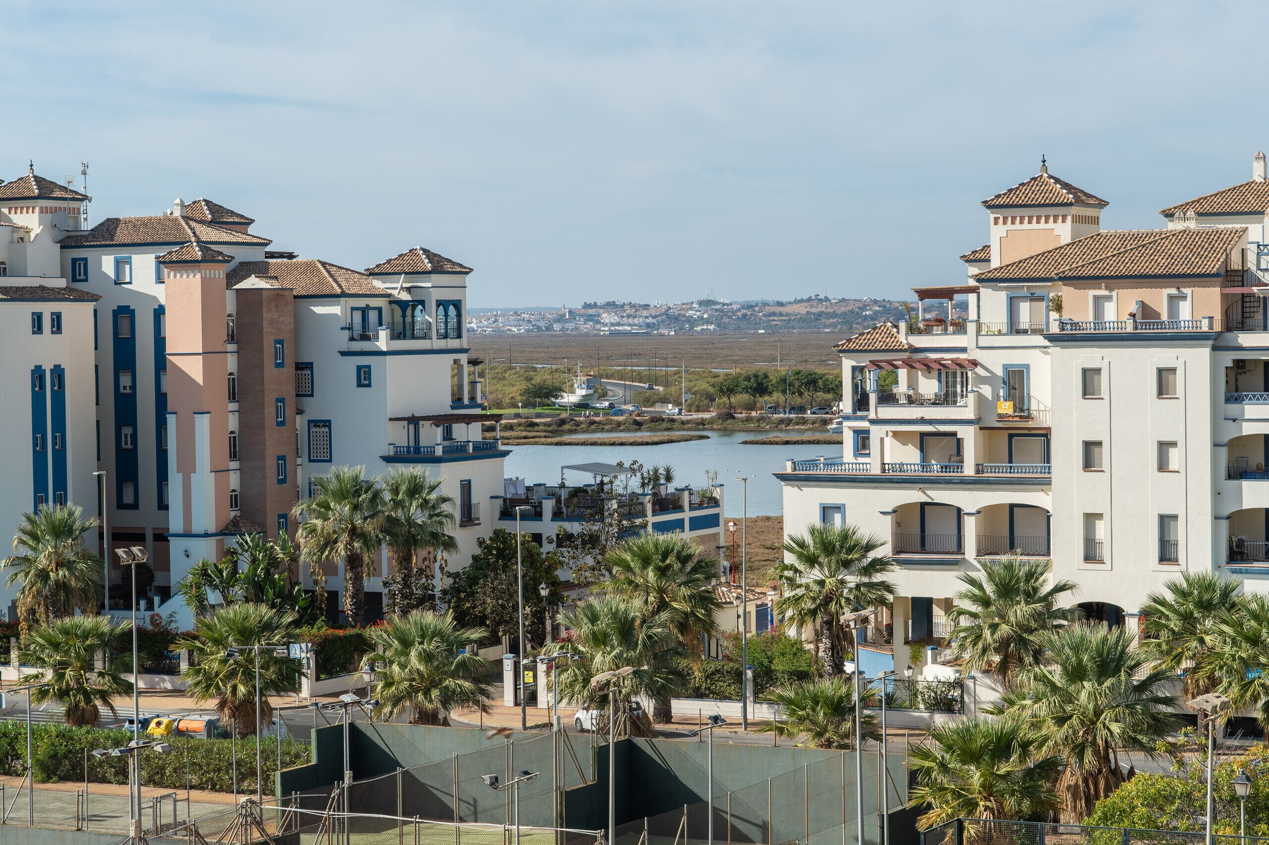 A coastal residential area with multi-story buildings, a marina, and palm trees.