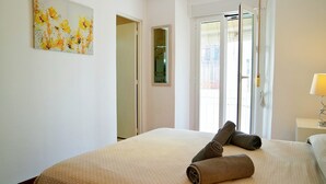 Ein Hotelzimmer mit einem Bett, einem Gemälde, einem Spiegel und einem Fenster mit Jalousien.