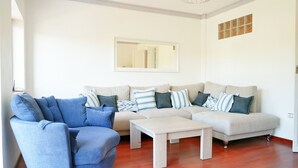 Ein Wohnzimmer mit einem beigen Sofagarnitur, einem blauen Sessel und einem Holztisch.