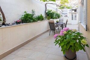A sunlit patio with a tiled floor, a table with chairs, and various potted plants. - Rooms Batina (Dubrovnik)