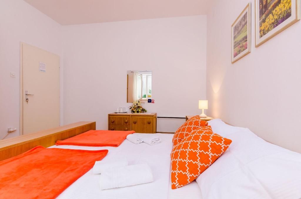 Une chambre d’hôtel avec un lit, une commode en bois, un miroir et une porte.