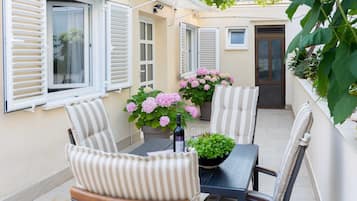 A patio with a table, chairs, and potted plants.