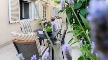 Eine Terrasss mit Tisch und Stühlen, umgeben von Pflanzen und Blumen.