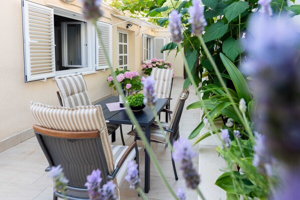 An outdoor patio with a table and chairs, surrounded by plants and flowers. - Rooms Batina (Dubrovnik)