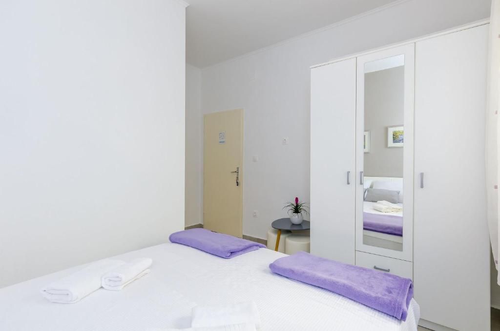 Habitación de hotel con cama, armario, una mesita con planta y una puerta.