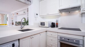 Eine moderne Küche mit weißen Schränken, einer eingebauten Mikrowelle, einer Kaffeemaschine und einer schwarzen Induktionskochplatte.