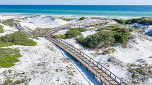 Una pasarela de madera que conduce a una playa con aguas azul cristalino.