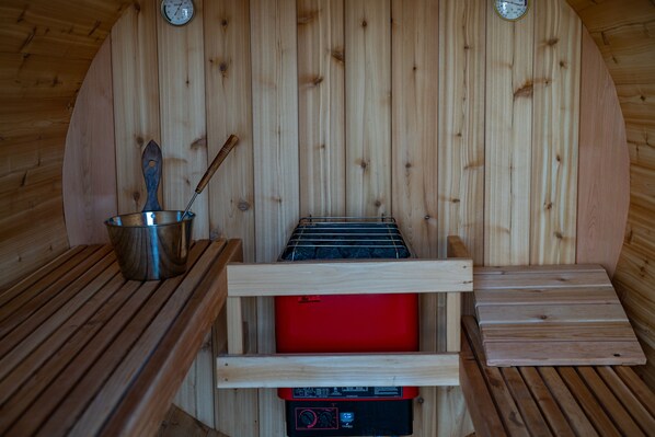 Un cuarto de sauna con paredes de madera, un banco para sauna, una mesa de madera y un calentador de sauna.