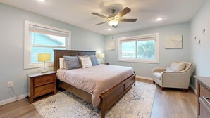 A bedroom with a bed, nightstands, a chair, a ceiling fan, and two windows. - 2nd Floor, Shared Pool and Hot Tub, Golf Cart Access (Port Aransas)