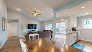 A spacious living area with a dining table, a sofa, and a ceiling fan. - 2nd Floor, Shared Pool and Hot Tub, Golf Cart Access (Port Aransas)