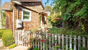 A wooden house with a fenced yard, a garage, and a red umbrella. - Lazy Bear Beach House (Capitola)