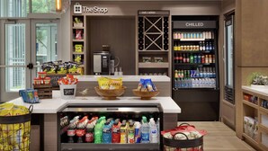 A store with shelves stocked with snacks, a refrigerated section, and a coffee machine. - Hilton Garden Inn Austin North - Near the Domain (Austin)