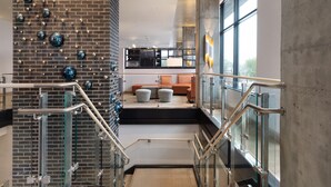 A modern interior with a brick wall, glass railings, and a seating area with cushions.