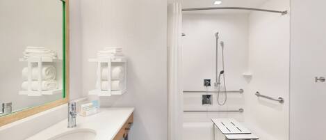 A modern bathroom with a sink, mirror, and shower area.
