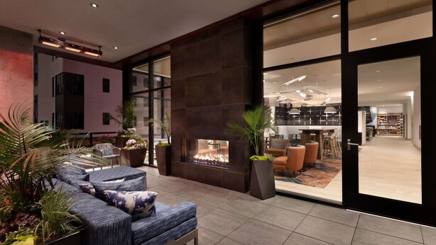 A modern living room with a fireplace, seating area, and large windows.