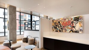 A modern interior with a large artwork of a musician, seating areas, and large windows. - Hampton Inn & Suites Watertown Boston (Watertown)