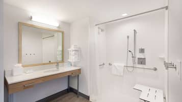 A modern bathroom with a wooden vanity, a large mirror, a shower with a glass door, and a white sink.