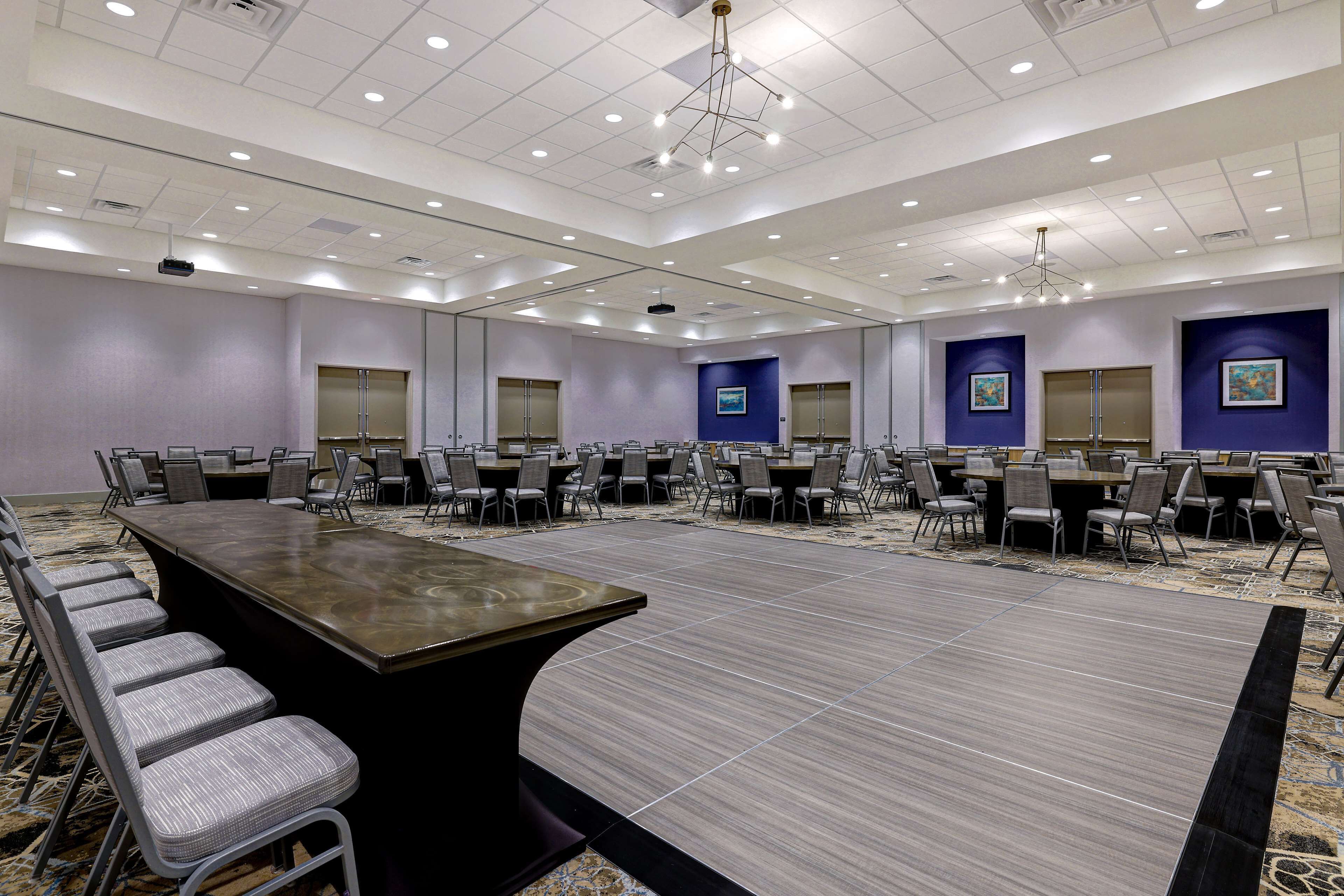 A large conference room with a long table and multiple chairs, equipped with a projector and a large screen.