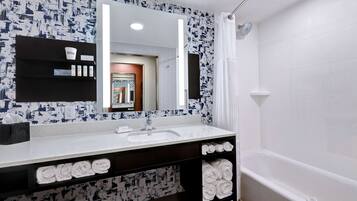 A modern bathroom with a white sink, a large mirror, and a shower.