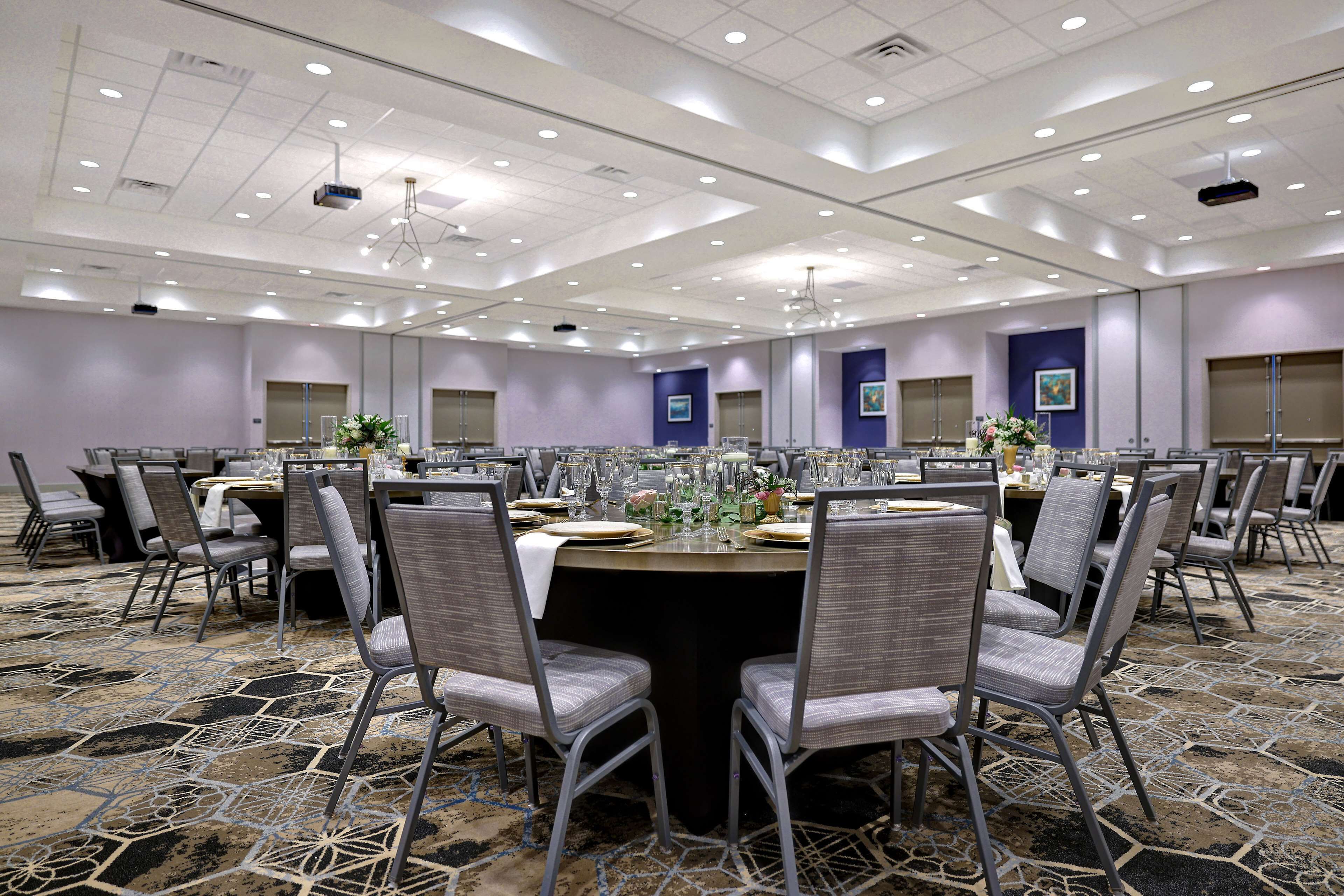 Une salle de conférence avec des tables rondes, des chaises et un tapis à motifs.
