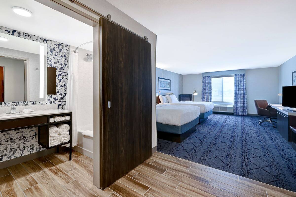 Ein Hotelzimmer mit Bad, Bett, Schreibtisch und Stuhl.