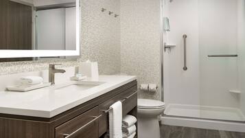 A modern bathroom with a large mirror, white sink, and a walk-in shower.