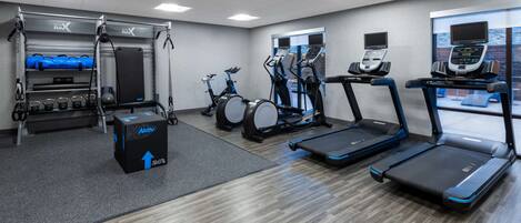 A gym with treadmills, stationary bikes, and a weightlifting area.