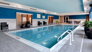 An indoor swimming pool with clear water, surrounded by lounge chairs and potted plants. - Hampton Inn & Suites Canal Winchester Columbus (Canal Winchester)