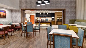 A modern hotel lobby with a central bar area, seating arrangements, and a patterned wall. - Hampton Inn & Suites Canal Winchester Columbus (Canal Winchester)