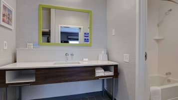 A modern bathroom with a white sink, a mirror with a green frame, a towel rack, and a shower area.