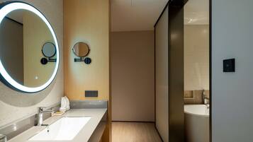 Un baño moderno con dos lavamanos, un espejo grande con luz y una bañera.