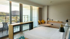 A modern hotel room with a large bed, a desk, and a balcony with a view of the city. - Hilton Garden Inn Zhuhai Hengqin Sumlodol Park (Zhuhai)