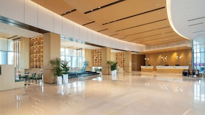 A spacious lobby with a reception desk, seating areas, and bookshelves. - Hilton Garden Inn Zhuhai Hengqin Sumlodol Park (Zhuhai)