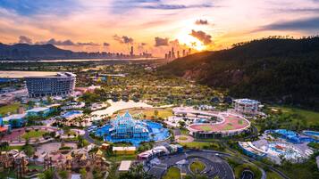 A large resort with multiple swimming pools, a central building with a blue roof, and a surrounding road network.