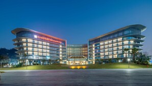A modern hotel with a curved facade, multiple floors, and a well-lit entrance area. - Hilton Garden Inn Zhuhai Hengqin Sumlodol Park (Zhuhai)