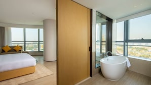 A modern hotel room with a large bed, a bathtub, and a large window offering a city view. - Hilton Garden Inn Zhuhai Hengqin Sumlodol Park (Zhuhai)