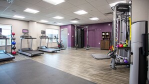 A gym with treadmills, elliptical machines, and a weightlifting station.
