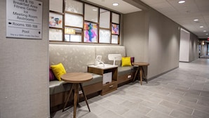 A hotel lobby with a seating area, a sign indicating the location of the breakfast area, fitness center, ice, meeting room, and restrooms.