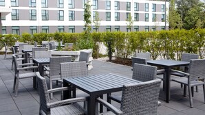 An outdoor patio area with wicker furniture and a modern building in the background.