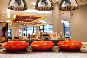 A modern interior with a glass-top buffet table displaying three orange covered dishes.