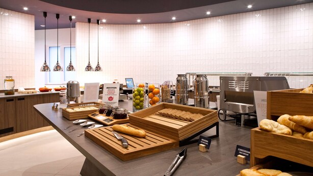 A modern breakfast buffet with wooden serving trays, a variety of breads, pastries, and fruits.