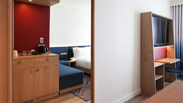 A hotel room with a bed, a desk, a chair, a wardrobe, and a television.