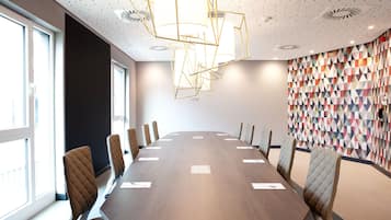 Un salón de conferencias con una larga mesa, sillas y un papel tapiz estampado.