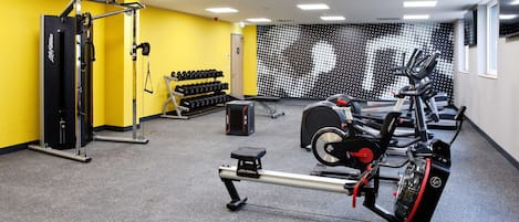 Un gimnasio con máquinas de pesas, mancuernas y cintas de correr.