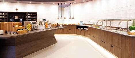 A modern kitchen with a curved counter, wooden cabinets, and various appliances.