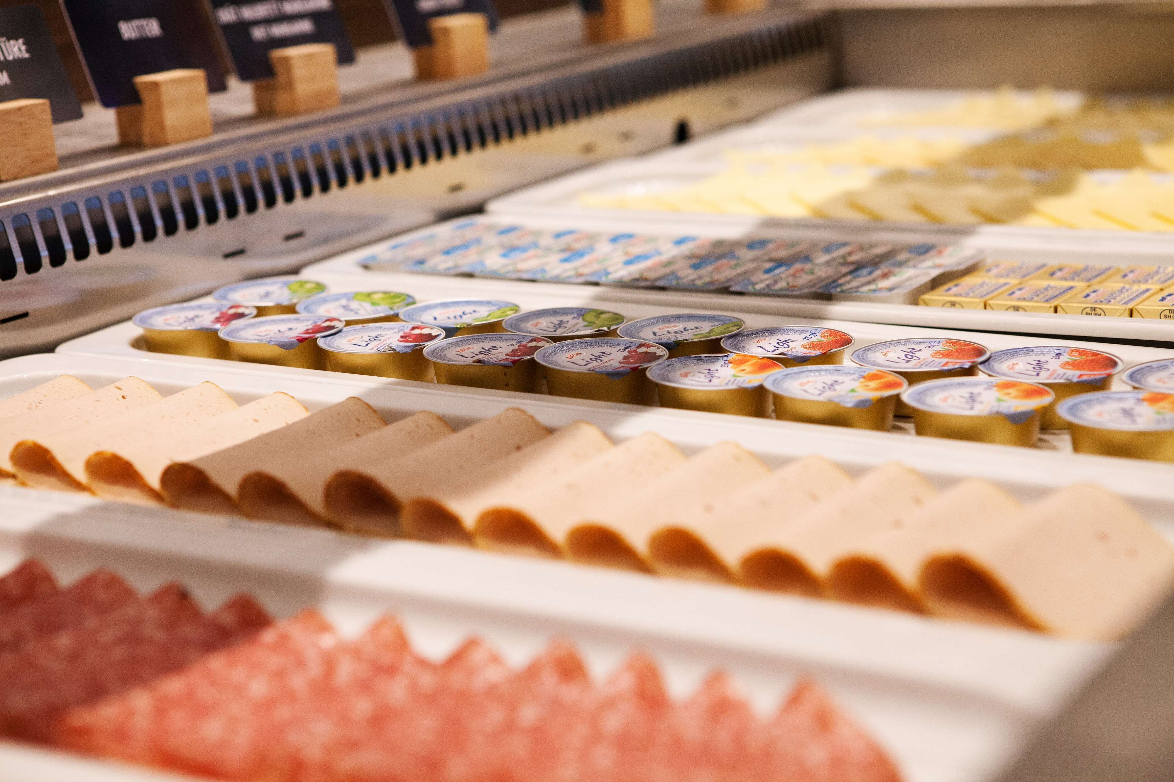 A deli display with various types of cheese and butter.
