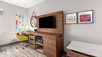 Quarto moderno com escrivaninha de madeira, televisão de tela plana, cadeira amarela e duas imagens emolduradas na parede.