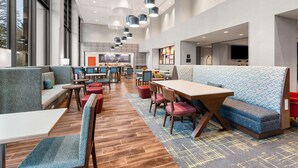 A modern restaurant with high ceilings, pendant lighting, and a mix of seating options including booths and tables.