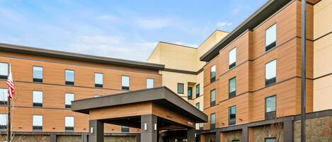 A modern hotel with a covered entrance, multiple floors, and a stone facade.