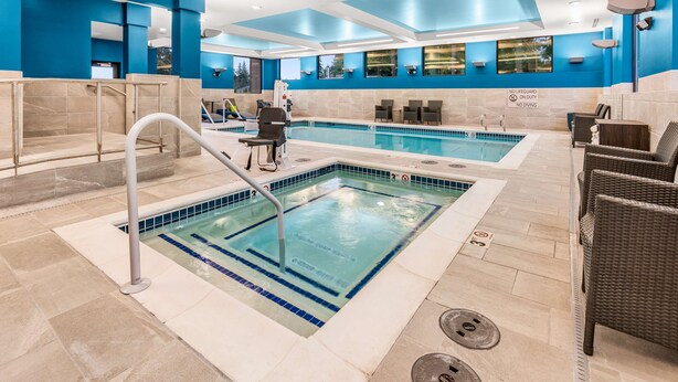 A swimming pool area with clear water, a lifeguard chair, and a sign indicating no lifeguard on duty.